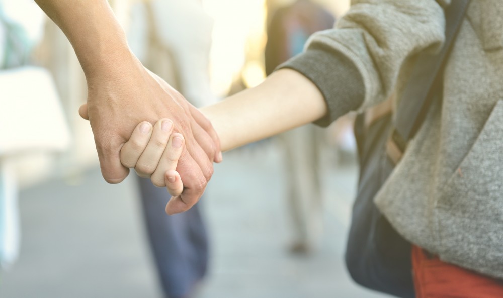 Adult holding a child's hand showing safe and supportive childcare